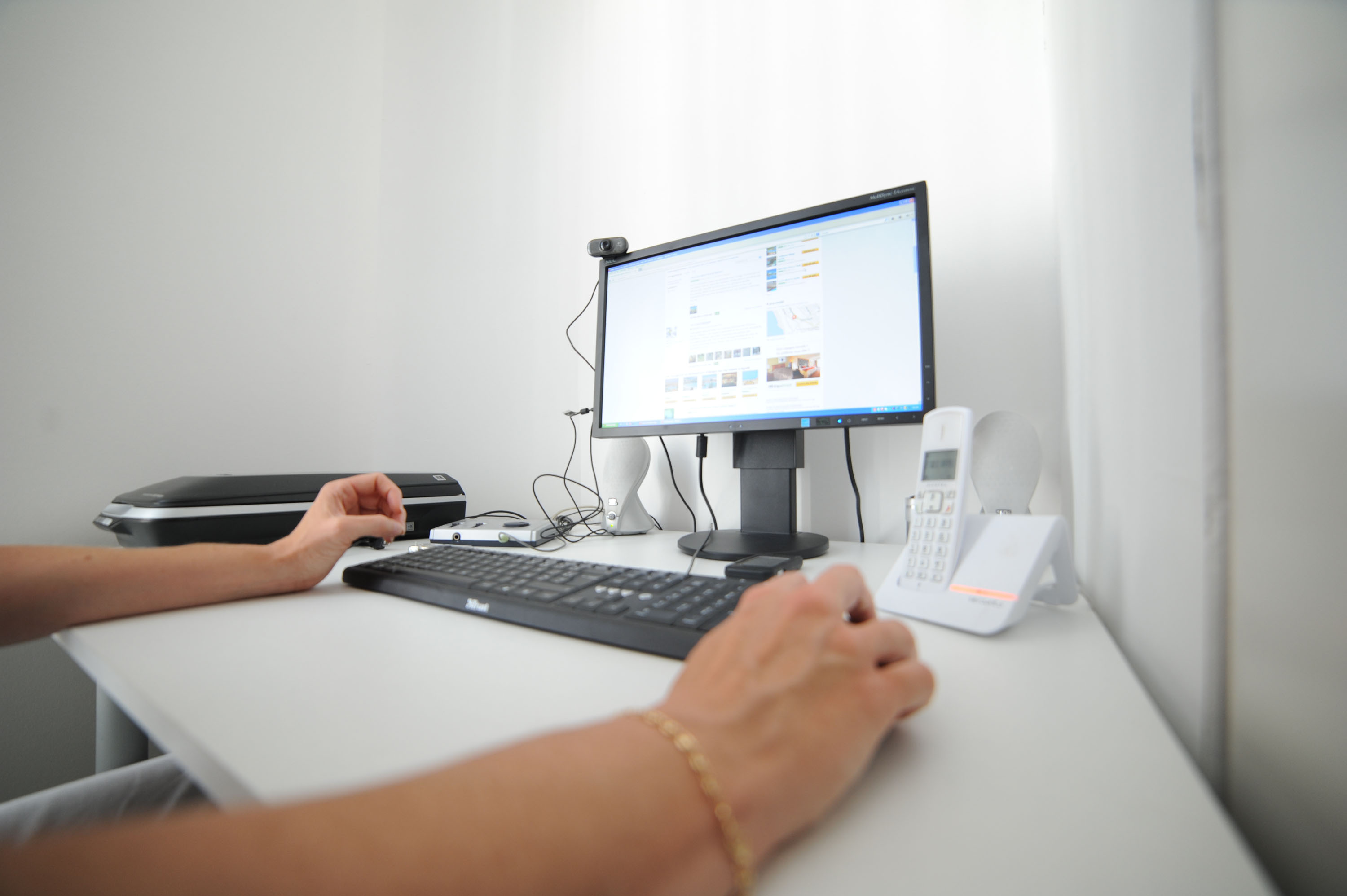 Femme assisse à un bureau devant un ordinateur équipé d'un clavier et d'une souris